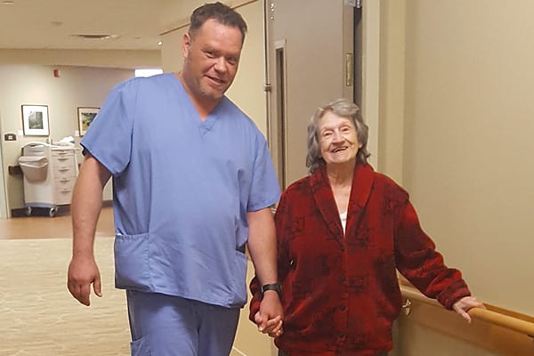Bethany Home nurse helping a resident walk down a hallway. Bethany Home nurse helping a resident walk down a hallway.
